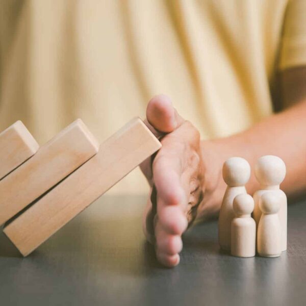 Father blocked the wooden block with his hand to show protection for the family. and support and help with advice The concept of family relationships that will connect to safety love and compassion