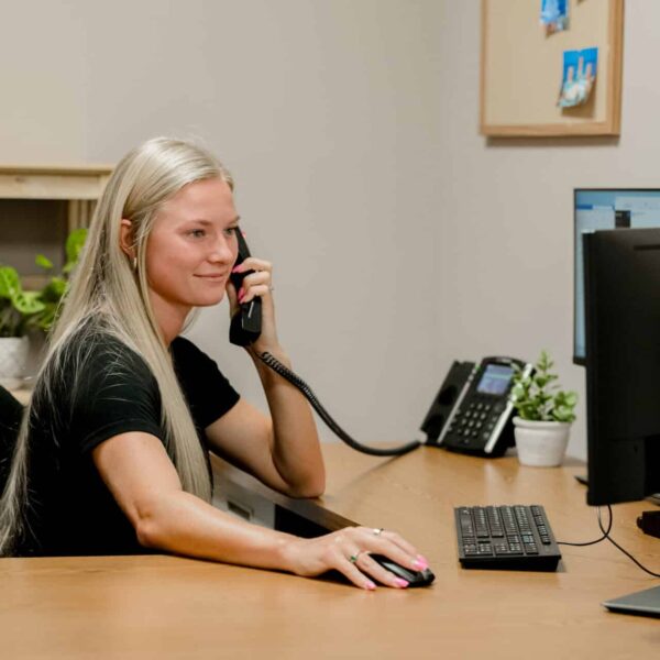 young woman on the phone while clicking her computer mouse