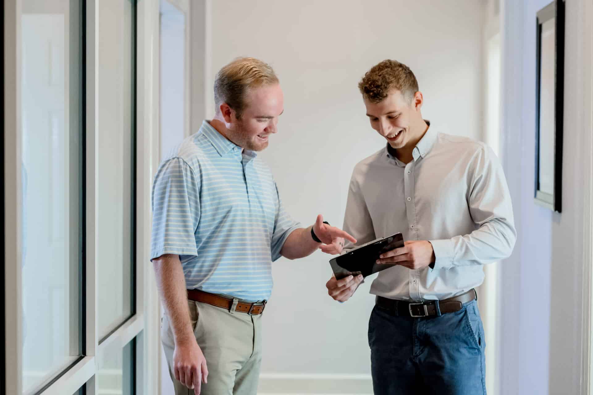 two men looking at a tablet with data displayed