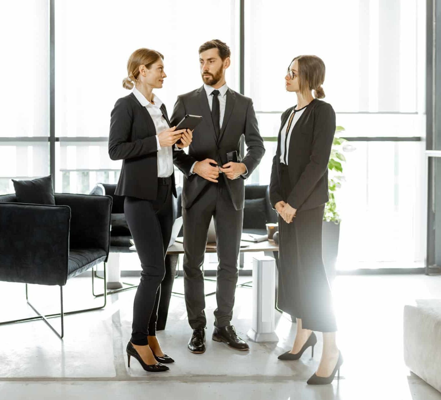 White-collar employees of financial institution or other big copany having some business, standing and talking in the luxury office