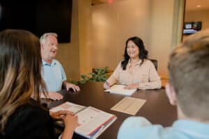 asian woman grinning while taking notes in a meeting