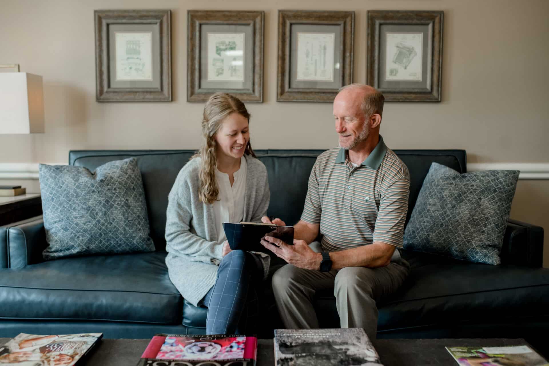 man showing a young woman a chart on a clipboard while sitting on a couch